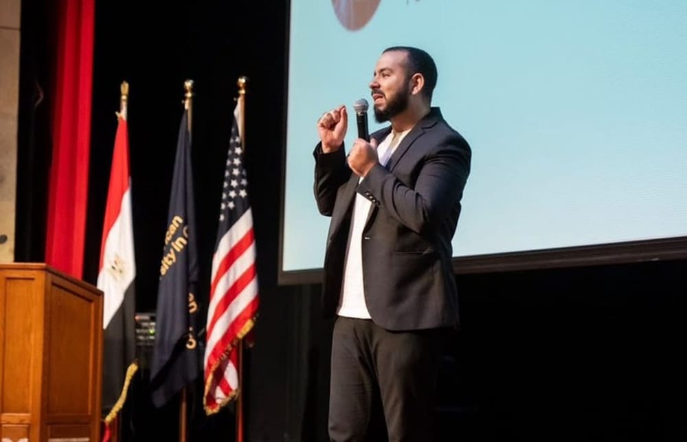 Mohannad Hesham speaking on stage, holding a microphone